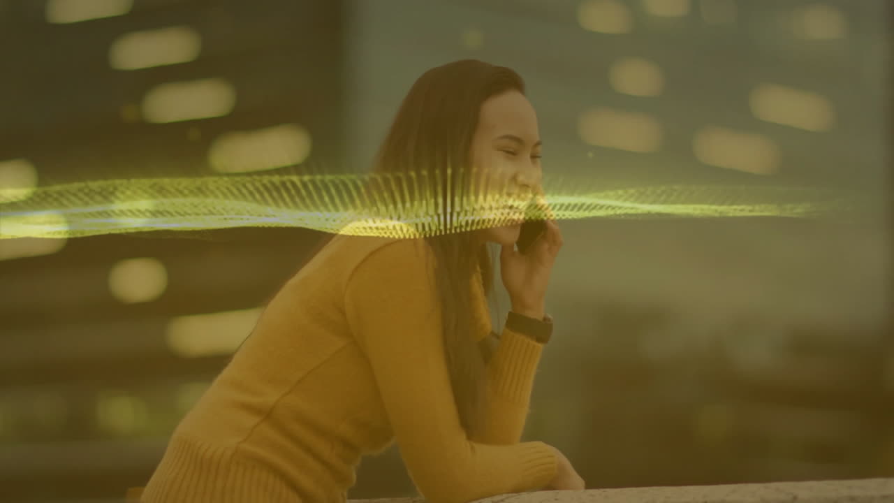 woman leaning on railing at rooftop, holding smartphone to ear, displaying neon wave for technology