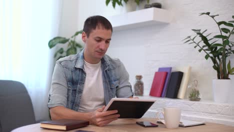 Professional-Creative-Man-Sitting-at-His-Desk-in-Home-Office,-Using-Smartphone,-Man-Using-Mobile-Phone,-Browsing-Through-Internet,-Social-Networks,-Media.