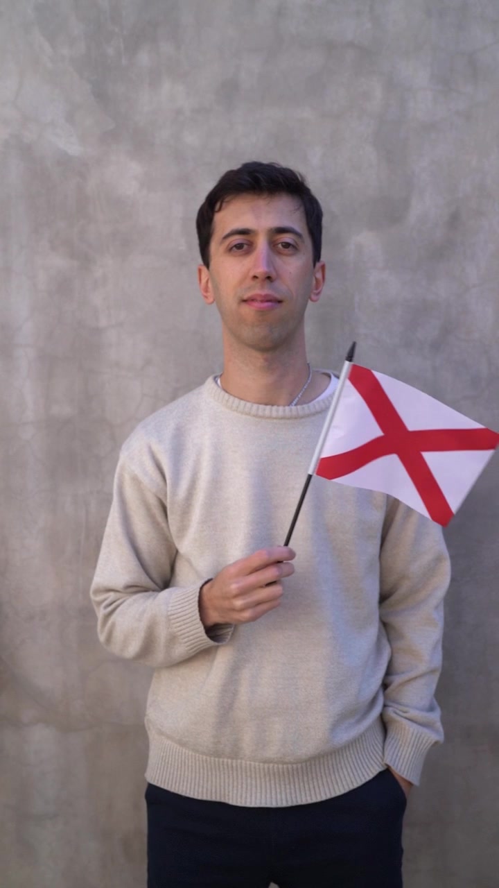 Mężczyzna machający flagą stanu Alabama. Koncepcja terytoriów USA. Ujęcie pionowe w zwolnionym tempie.