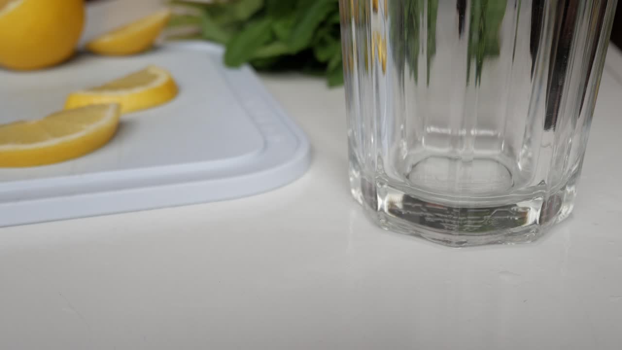 Lemon slices placed on a cutting board next to an empty glass, preparing lemonade