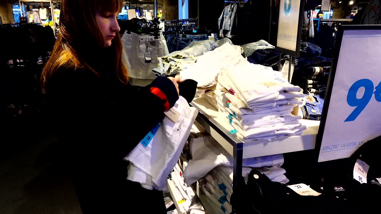 Shopping negli outlet in Europa. La ragazza sceglie i vestiti.