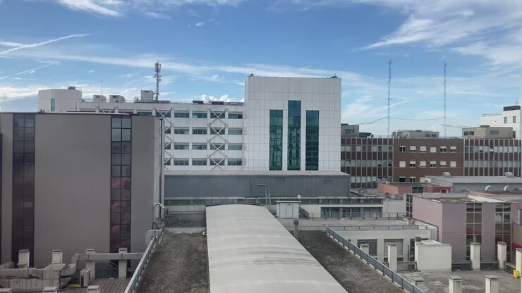Ripresa aerea dall'alto di tetti di ospedali e isolati urbani in cemento. Superfici industriali grigie evocano infrastrutture ospedaliere urbane, monotonia architettonica e ambiente cittadino denso