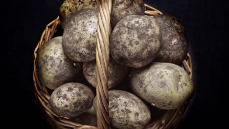 composition of vegetables, rotation of a basket with root vegetables, potatoes, on a black background