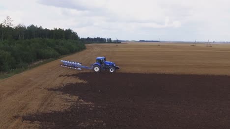 blue modern plowing tractor working in the field