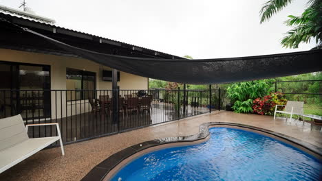 rainy day weather around tropical pool and recreational area under sun shade in backyard