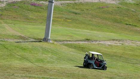 golf cart driving on a grassy hill