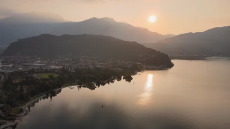 Cinematic-Aerial-View-of-Idyllic-Sunrise-Above-Garda-Lake-and-Riva-De-Garda-City-on-Summer-Morning