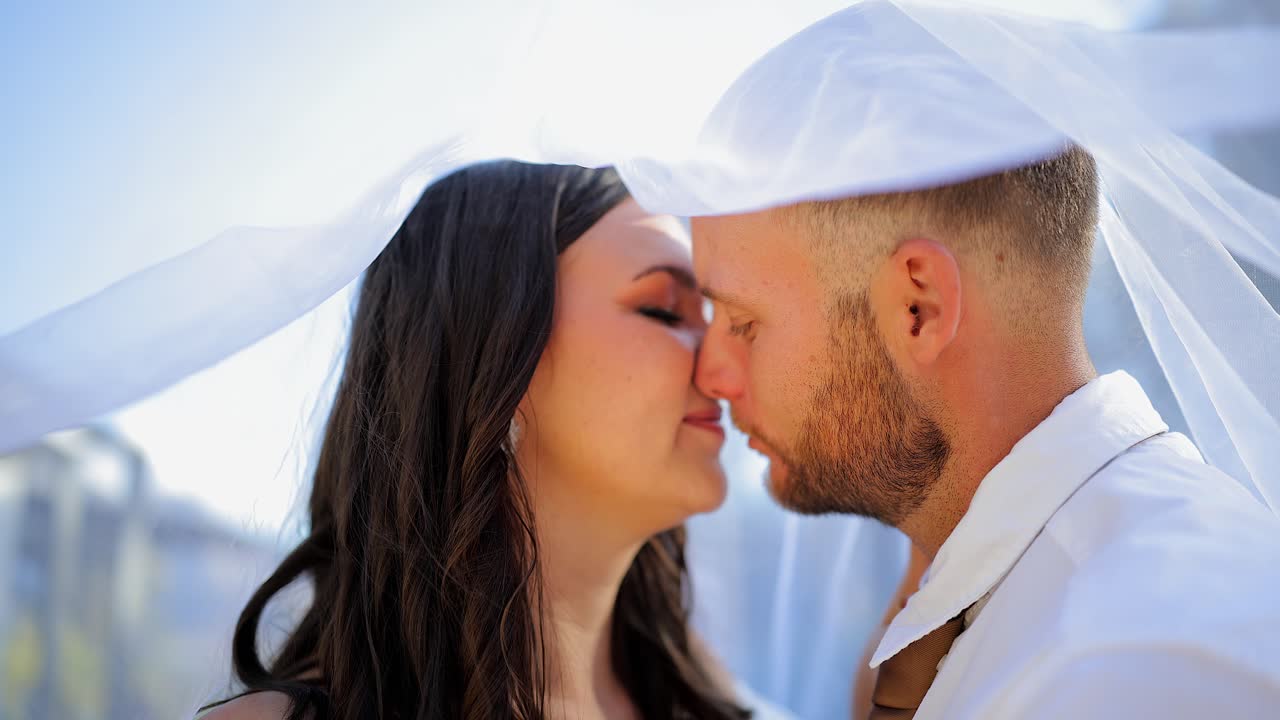 Amore, romanticismo: Sposi si baciano sotto un velo di pizzo in un primo piano in giardino.