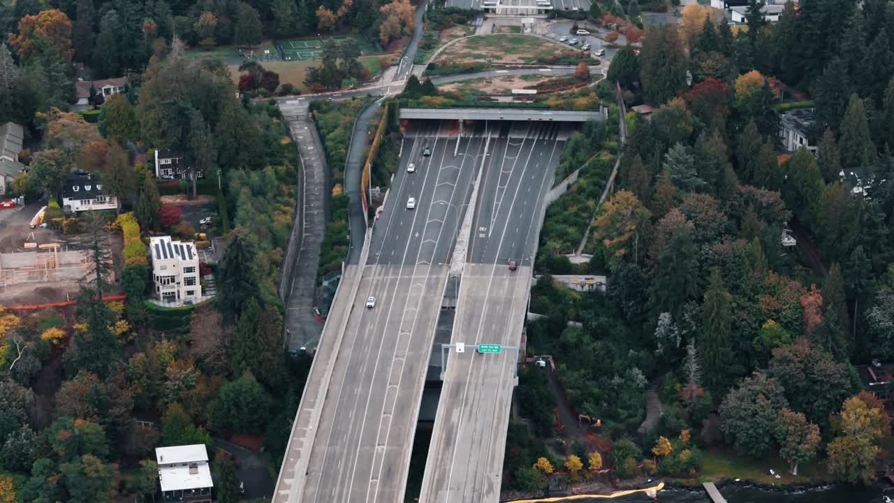 A freeway glides off the bridge and under green trees into the Seattle mainland