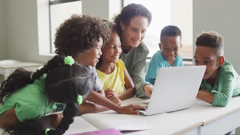 Video-of-happy-caucasian-female-teacher-explaining-lesson-on-laptop-to-diverse-pupils