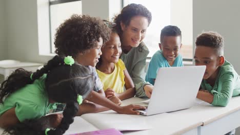 video of happy caucasian female teacher explaining lesson on laptop to diverse pupils