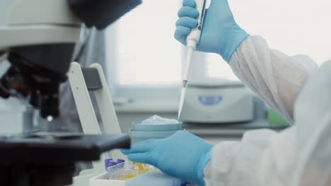 laboratory scientist using microscope and pipette