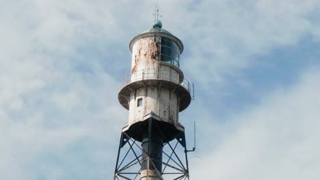 Static-shot-of-a-metallic-rusty-white-lighthouse-cabin-on-a-background-of-light-white-clouds