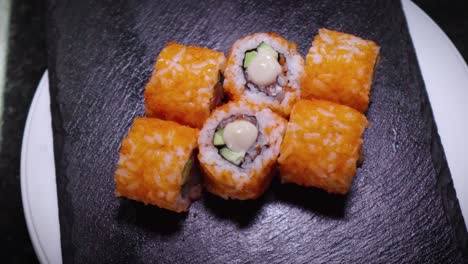 vista superior de rollos de sushi frescos girando en una placa de pizarra de piedra negra. fotografía de sushi de pescado, salmón, arroz, aguacate. comida deliciosa. comida tradicional asiática