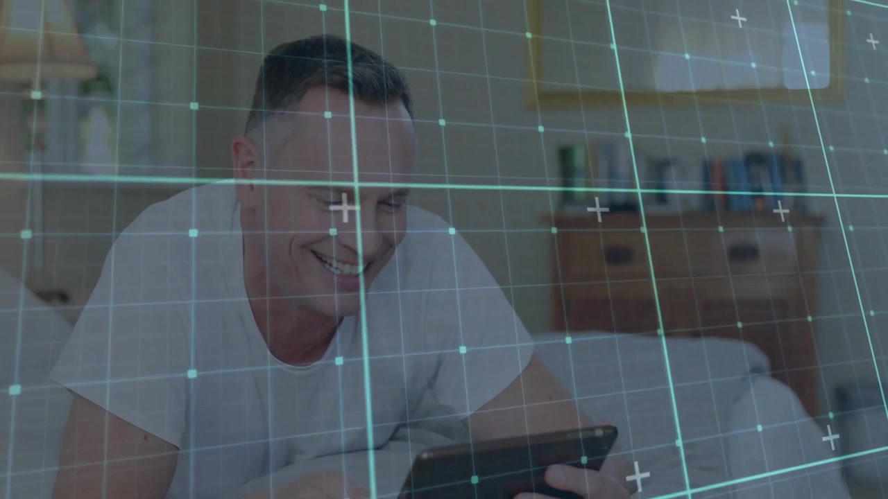 Man lying on bed, activating tablet for tech demo, showing grid overlay, tapping screen and smiling