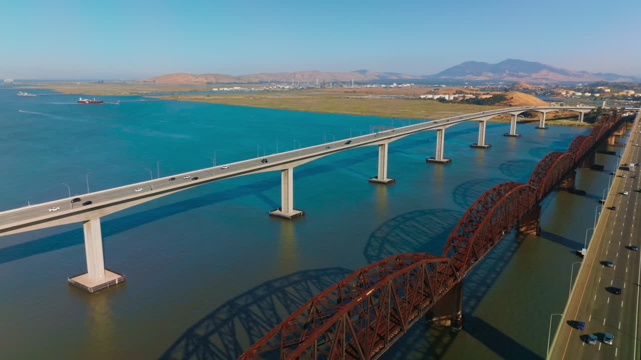 Three neighboring bridges over blue calm water of Carquinez Strait. Martinez-Benicia bridges with lots of cars on. Sunny clear day footage.