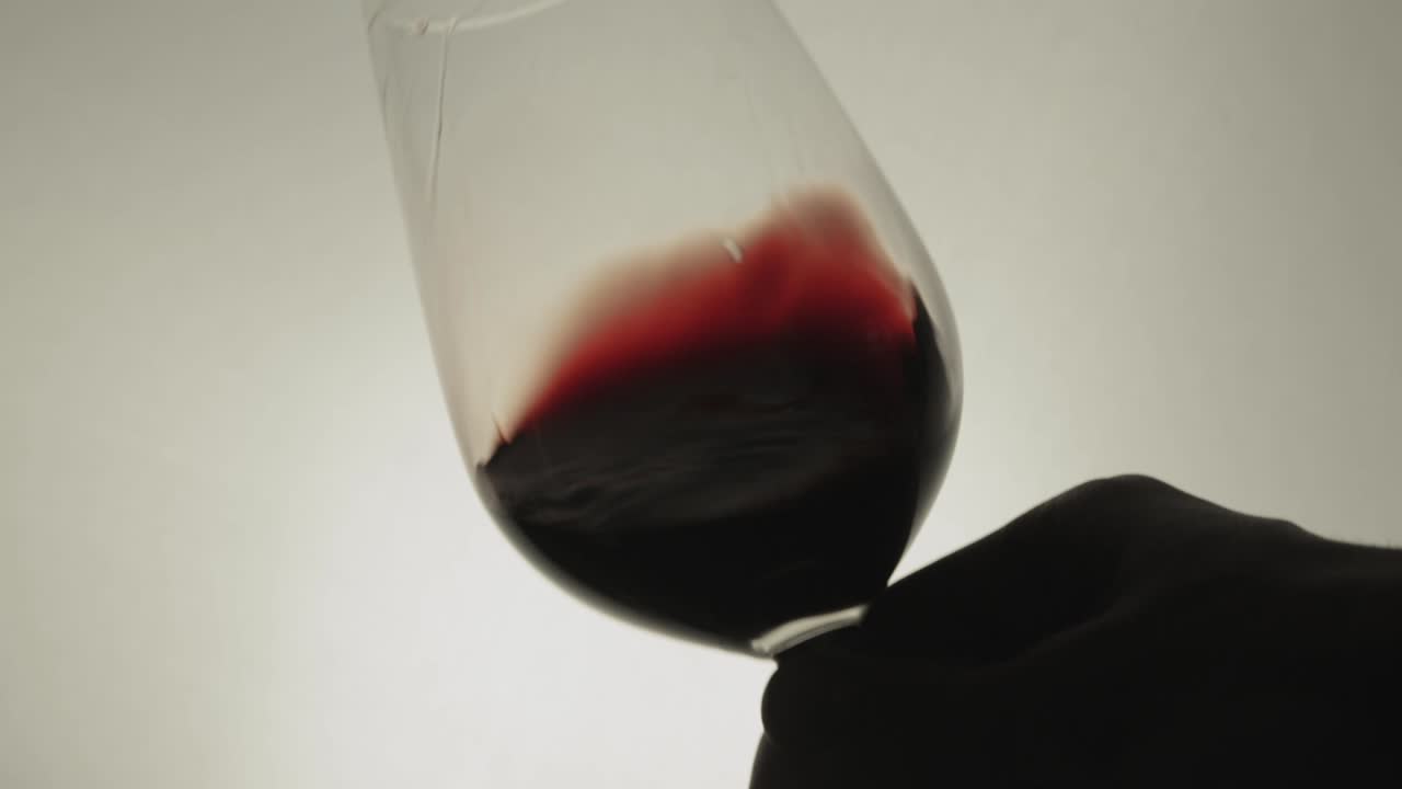 Far roteare vino rosso in un calice da vino su sfondo bianco - Primo piano