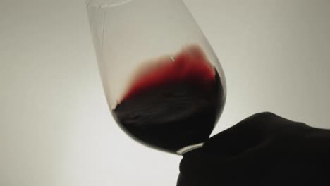 Swirling-red-wine-in-a-wineglass-in-white-background---Close-up