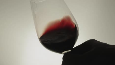 remolino de vino tinto en una copa de vino de fondo blanco - primer plano