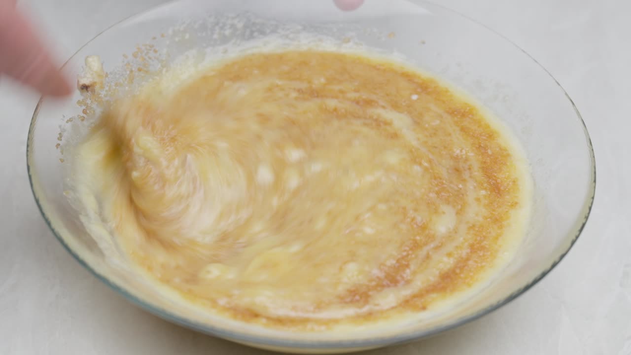 Top-down close-up of brown sugar added to banana bread batter and mixed with a fork