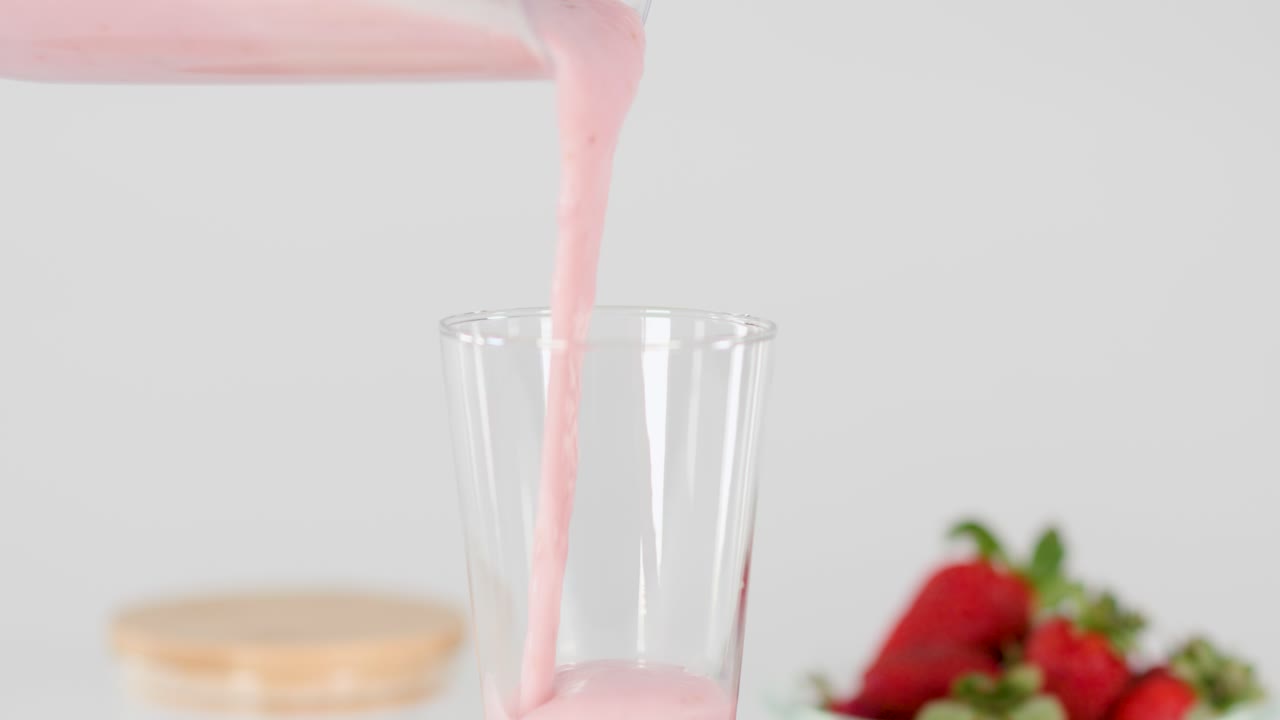 Strawberry smoothie being poured into a glass
