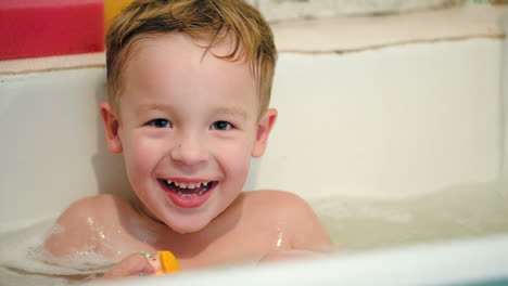 niño feliz en el baño con juguetes