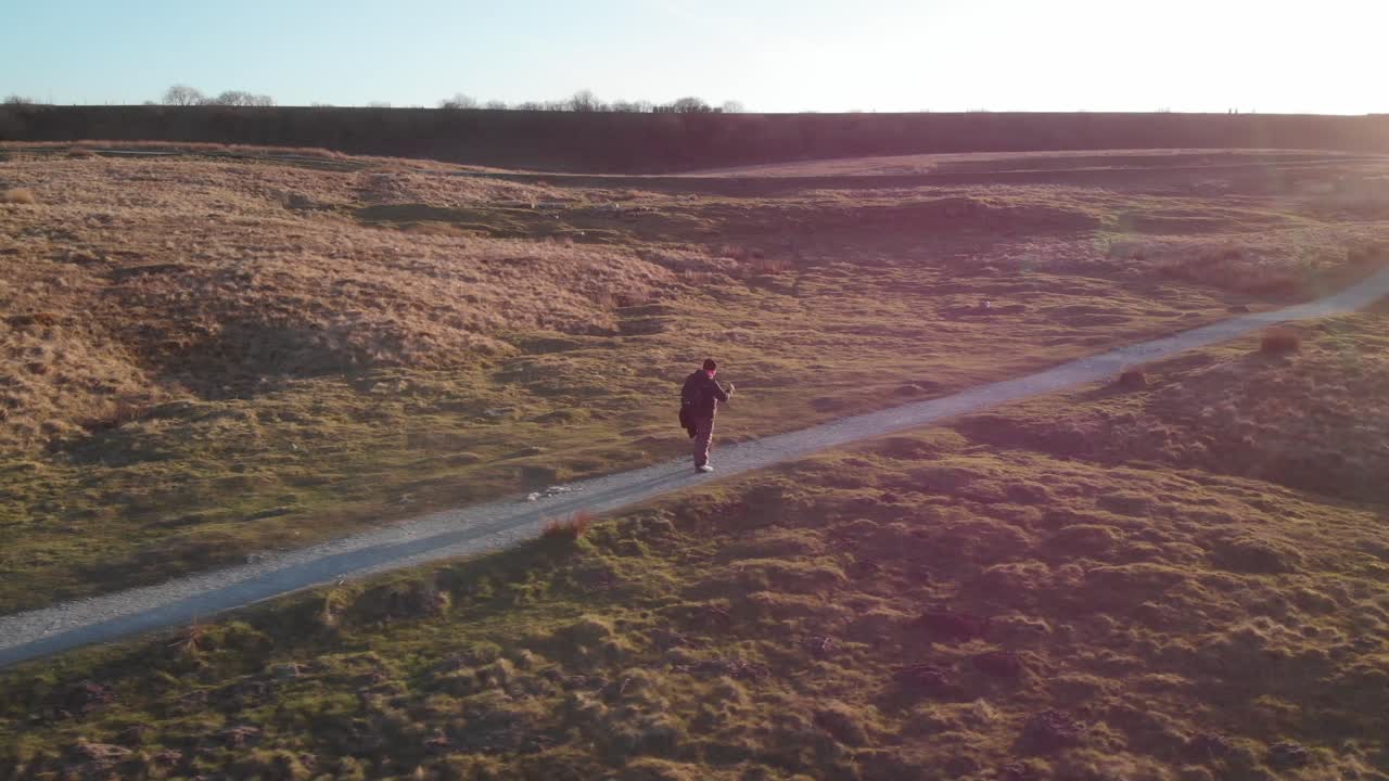 Inquadratura orbitale di un uomo che cammina verso il Viadotto di Ribblehead al tramonto.