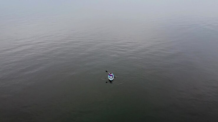 Aerial Drone shoots Girl on a kayak paddling on a cloudy day