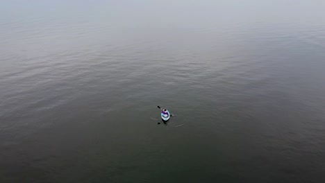 drone aéreo dispara a una chica en un kayak remando en un día nublado
