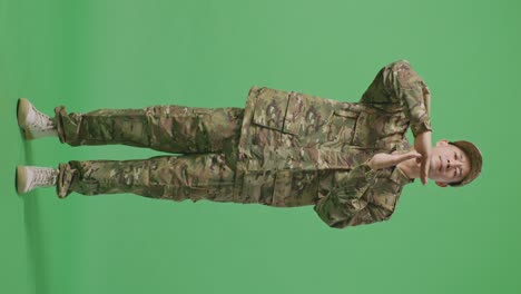 full body of asian man soldier looking at camera and showing time out hands gesture while standing in the green screen background studio