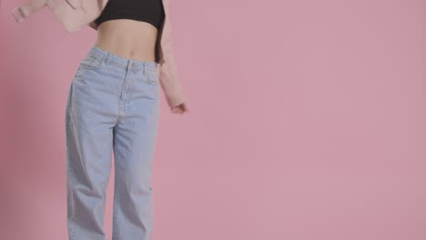 Close-Up-On-Legs-Of-Woman-Having-Fun-Dancing-Against-Pink-Studio-Background