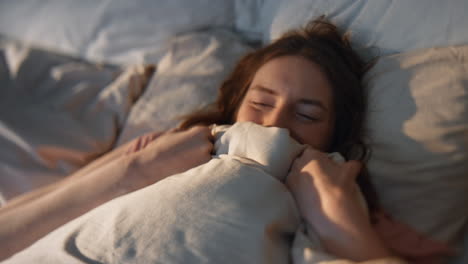 carefree girl stretching bed in sunlight closeup. happy female waking up early