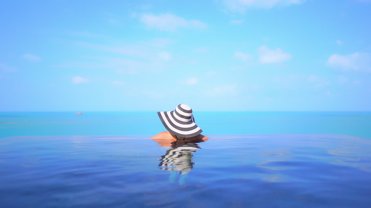 Classy Female With Floppy Summer Hat in Infinity Pool, View of Blue Endless Horizon