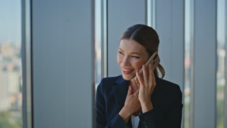 una mujer de negocios feliz comunicando por teléfono móvil en un primer plano panorámico de la oficina.