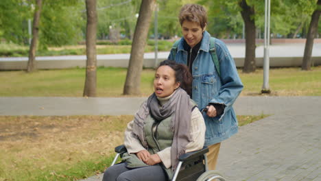 woman in wheelchair on walk in park with friend
