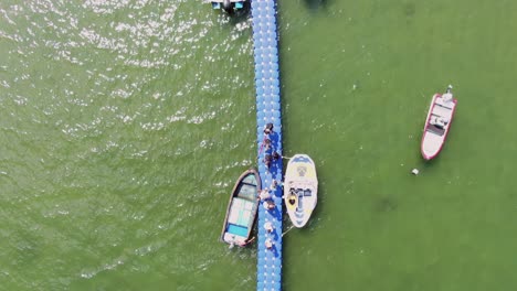 Locals-walking-on-a-small-pier-in-Hong-Kong-with-small-boats-in-the-water-on-a-summer-day