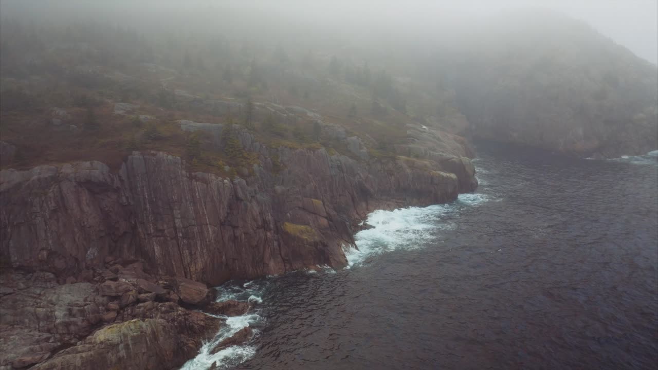 Morning fog hangs over the cliffs along the coast of Canada