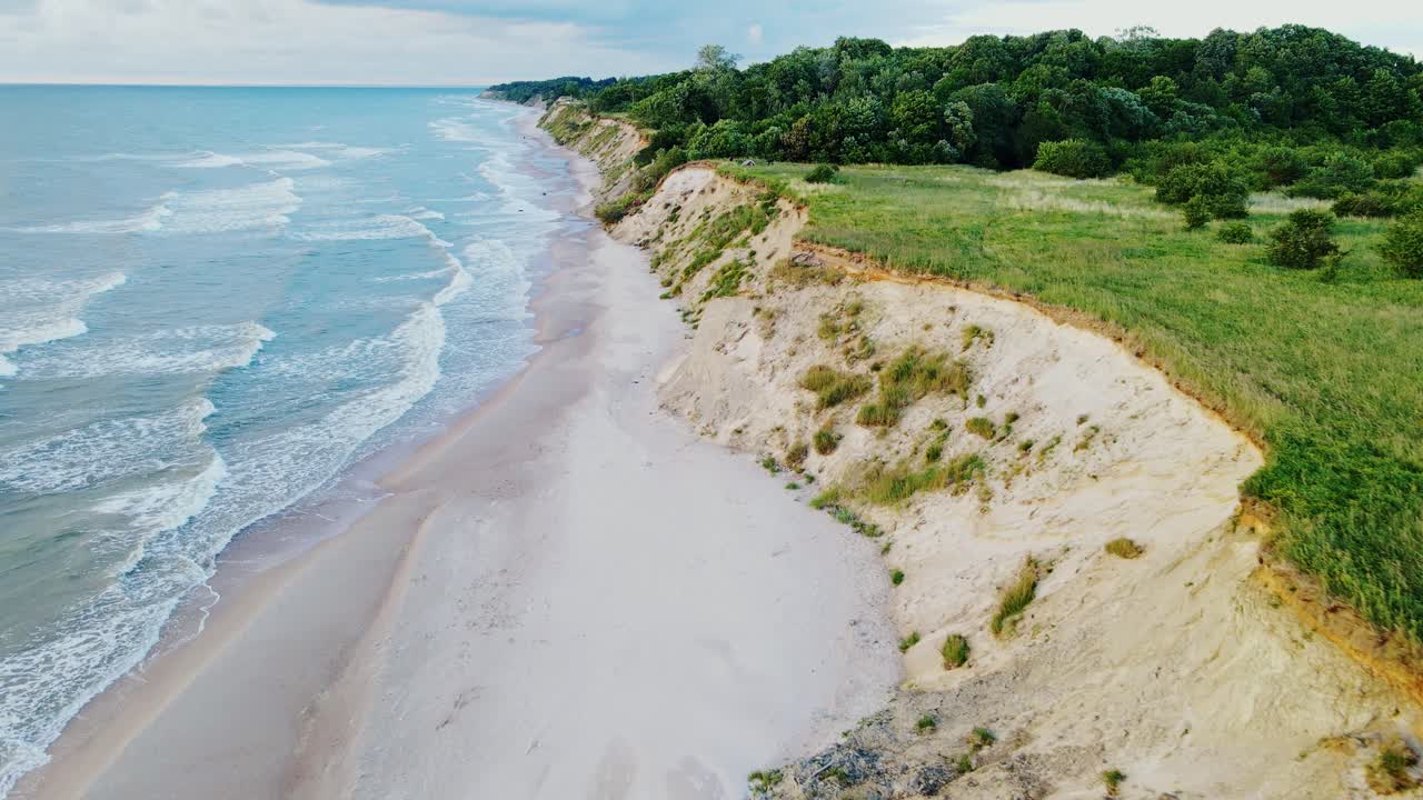 Golden-hour sunlight bathes Latvia’s rugged Baltic Sea cliffs, waves shape shore