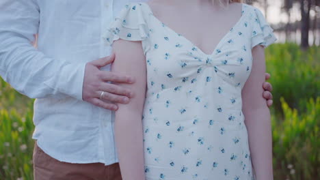 포르투갈 오바르 해변의 자연에서 손과 꽃 드레스에 초점을 맞추고 포옹하는 커플의 클로즈업