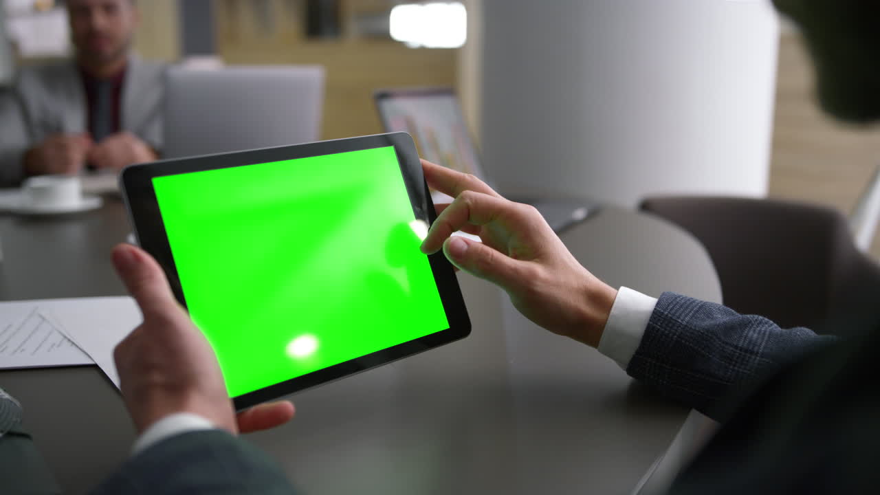 Coworker man scrolling tablet green screen browse web on business meeting table.