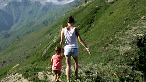 hiking woman with daughter on travel excursion walking in mountain landscape.