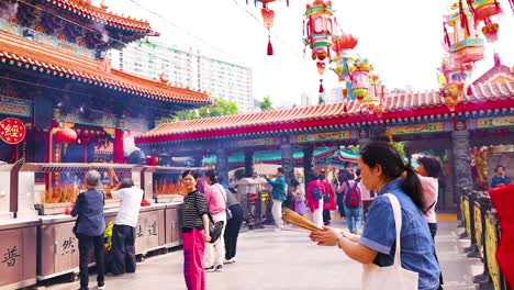 people praying and offering incense at temple