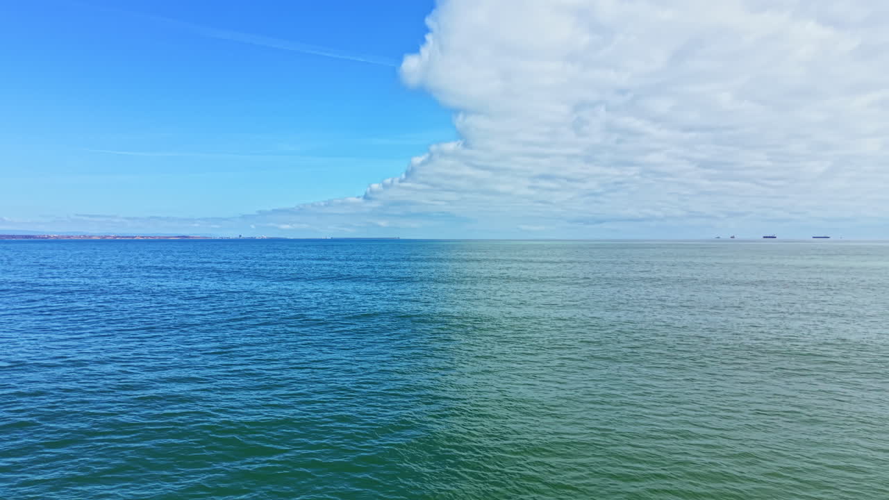 Ampia veduta delle acque oceaniche sotto un cielo azzurro con nuvole e navi all'orizzonte di giorno