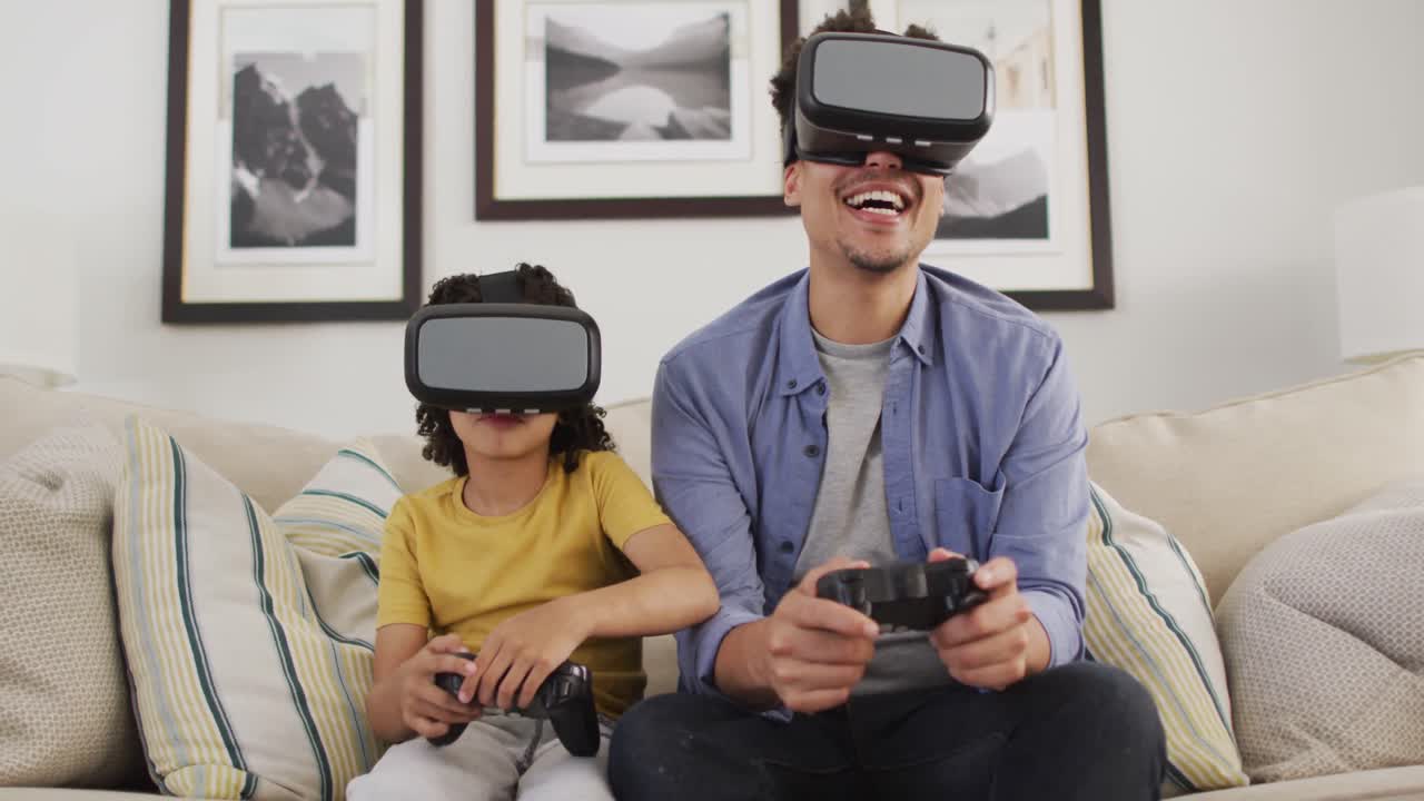 Uomo birazziale felice e suo figlio che giocano ai videogiochi indossando un visore VR