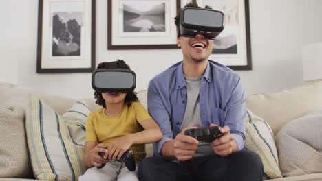 happy biracial man and his son playing video games wearing vr headset