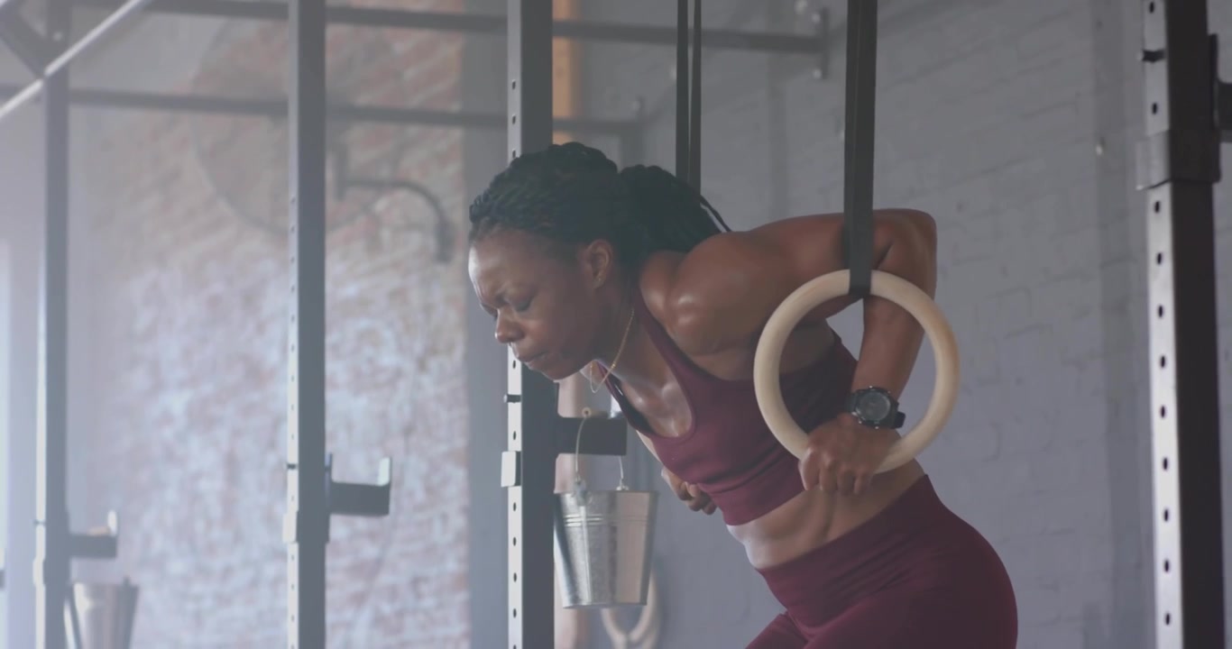 Female athlete gripping rings and executing dips, showing digital performance tracking overlays