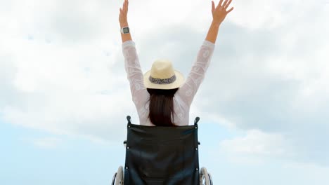 Vista-Trasera-De-Una-Mujer-Discapacitada-Sentada-Con-Los-Brazos-Arriba-En-Silla-De-Ruedas-En-La-Playa-4k