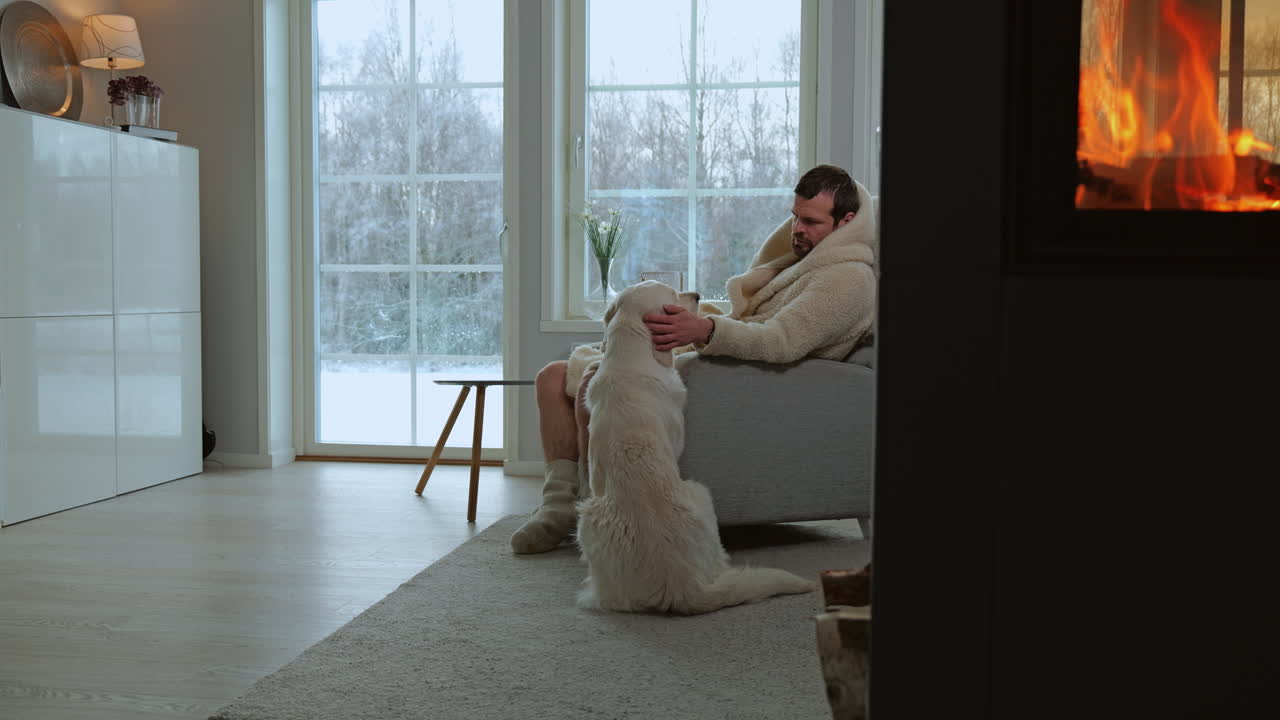 Man and dog chilling in the living room of a cozy house by the fire