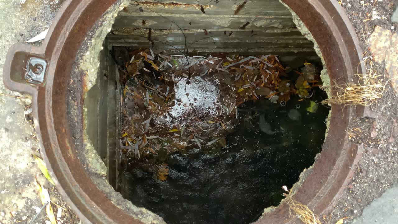 Looking down into an open manhole showing sewer with waste water.
