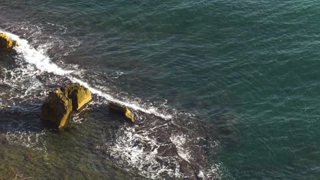 Subtropical-Waves-break-over-submerged-reef-and-jagged-rocks,-Denia-Spain